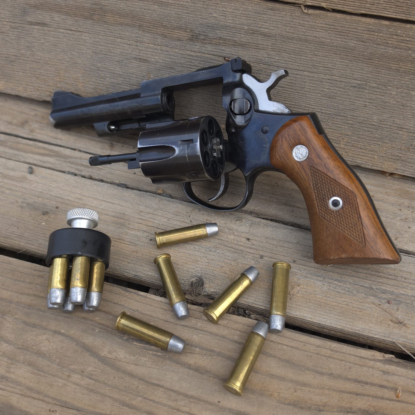 Blued Ruger Security-Six .357 Magnum revolver with 4 inch barrel on weathered wood, with loose cartridges and a loaded speedloader